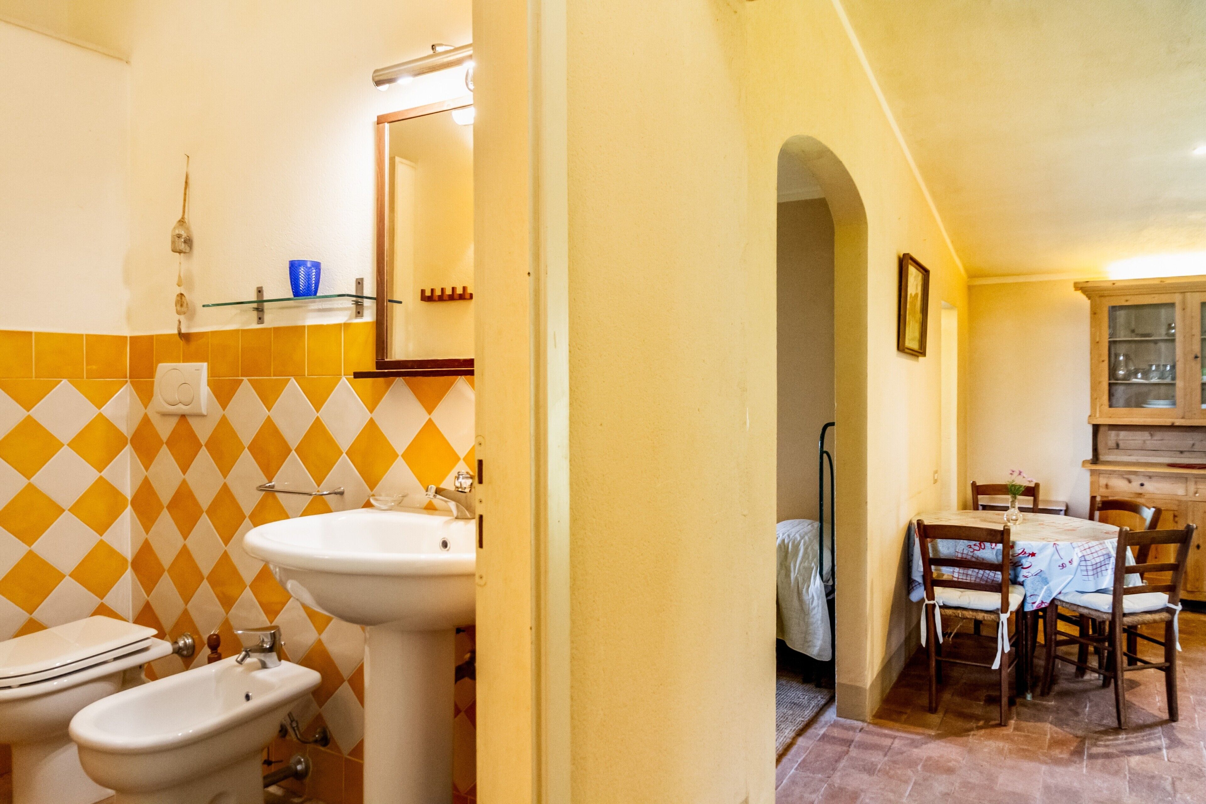 Ein Badezimmer mit Waschbecken, Bidet und Spiegel, sowie ein Essbereich mit Tisch und Stühlen.
