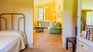 Un dormitorio con una cama, una ventana, un radiador, un sofá, un televisor y un aparador.