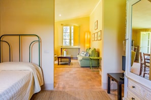 Ein Schlafzimmer mit Bett, Fenster, Heizkörper, einer Couch, einem Fernseher und einem Schminktisch.