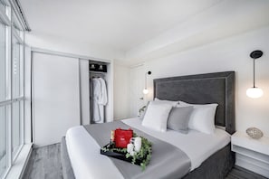 Ein modernes Schlafzimmer mit einem großen Bett, einem Kleiderschrank, einem Nachttisch und einem Beistelltisch.