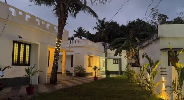 A residential area with white buildings, a paved pathway, and potted plants.