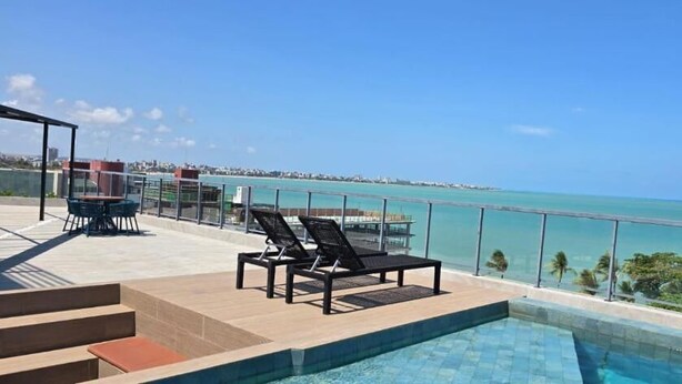 A rooftop pool with lounge chairs and a view of the ocean. - Mare Nostrum - João Pessoa - Beira Mar  (João Pessoa)