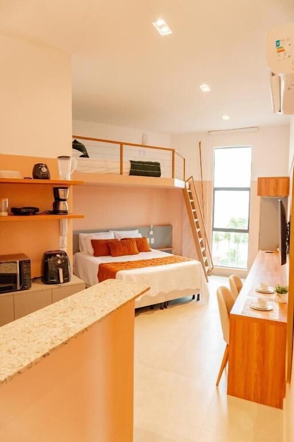 A compact hotel room with a bunk bed, kitchenette, and a small dining area.