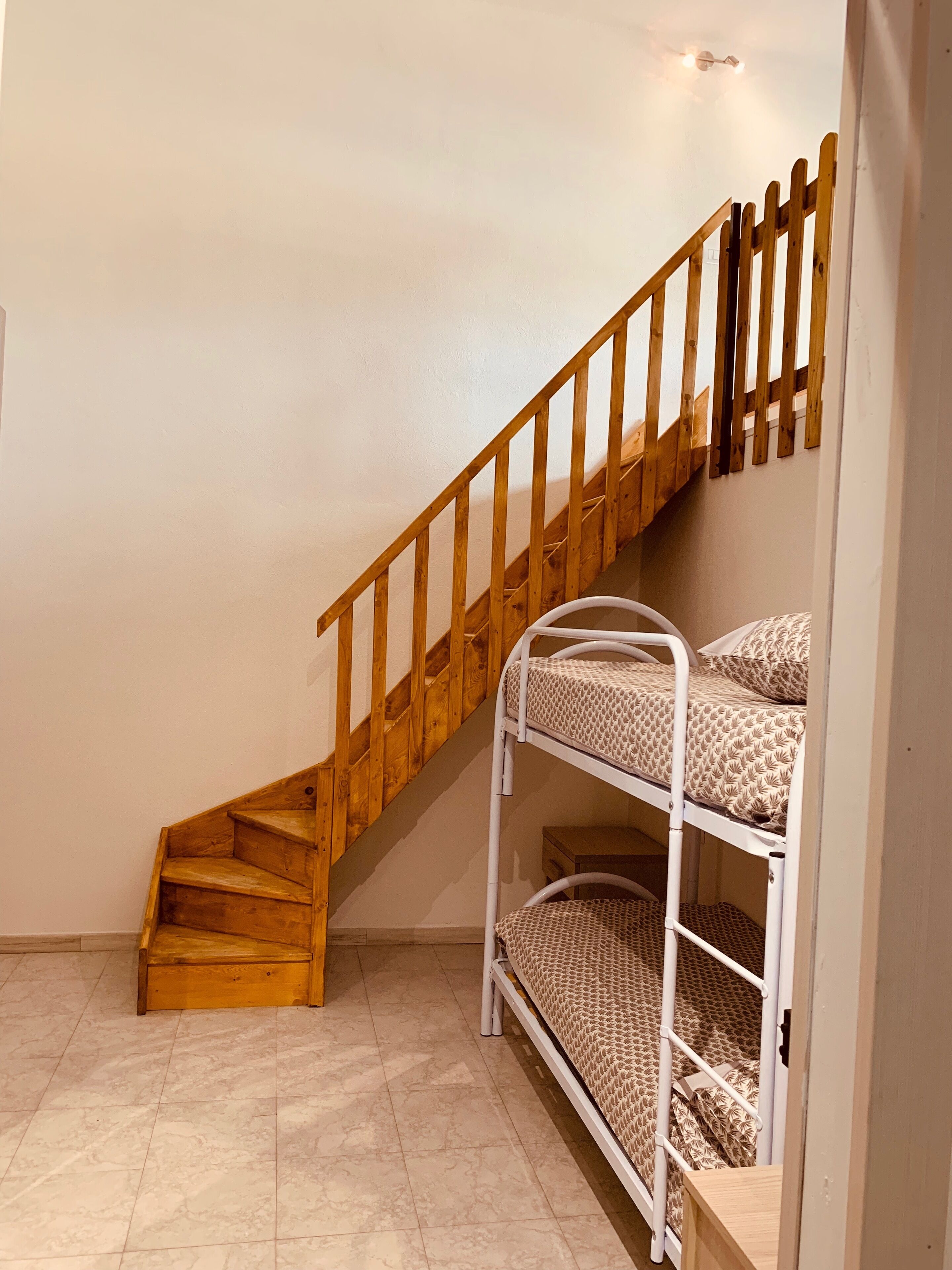 Eine Treppe mit Holzgeländern, die zu einem Schlafbereich mit Etagenbetten führt.