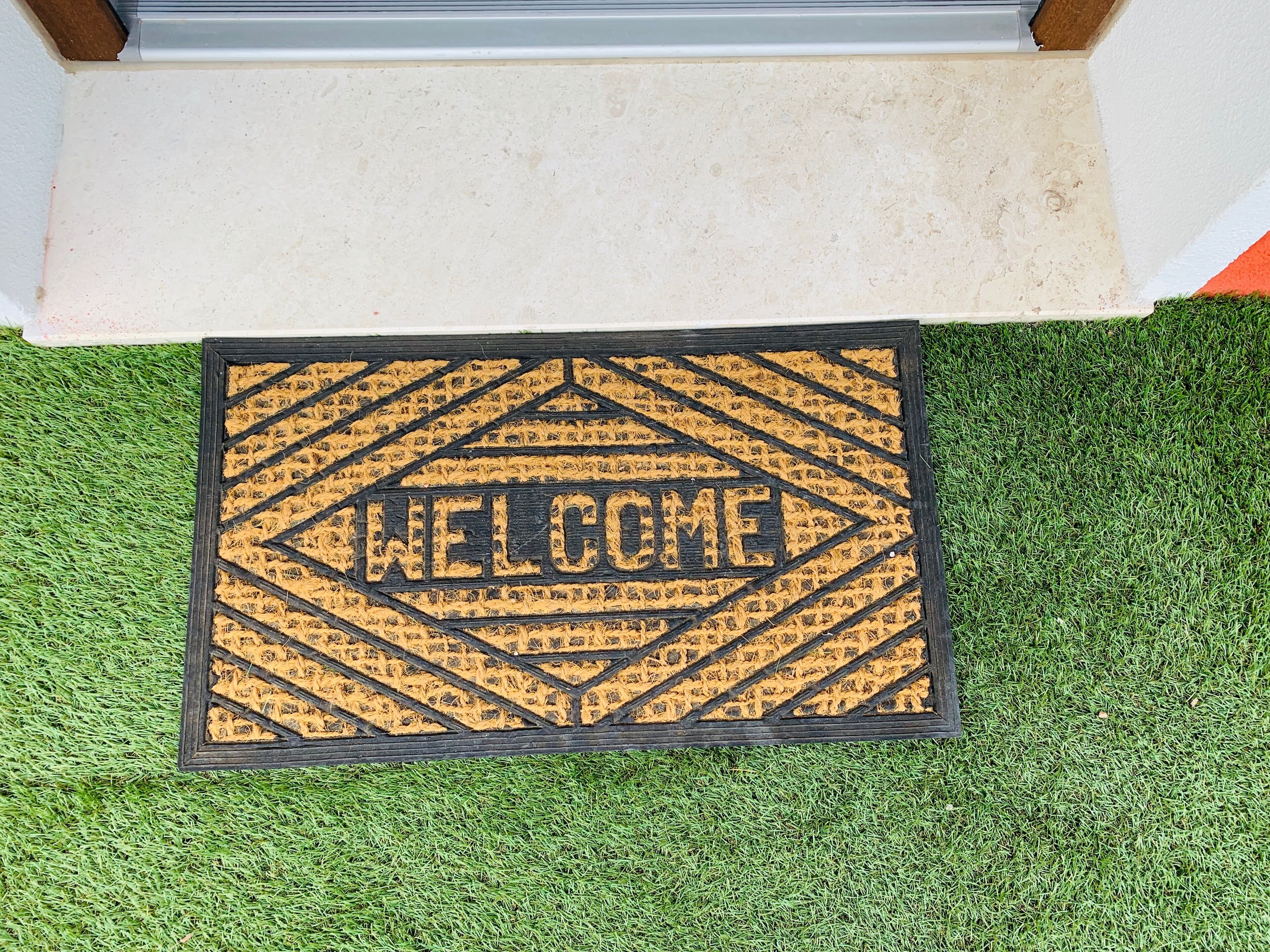 Una felpudo con un diseño geométrico y la palabra 'WELCOME' en el centro.