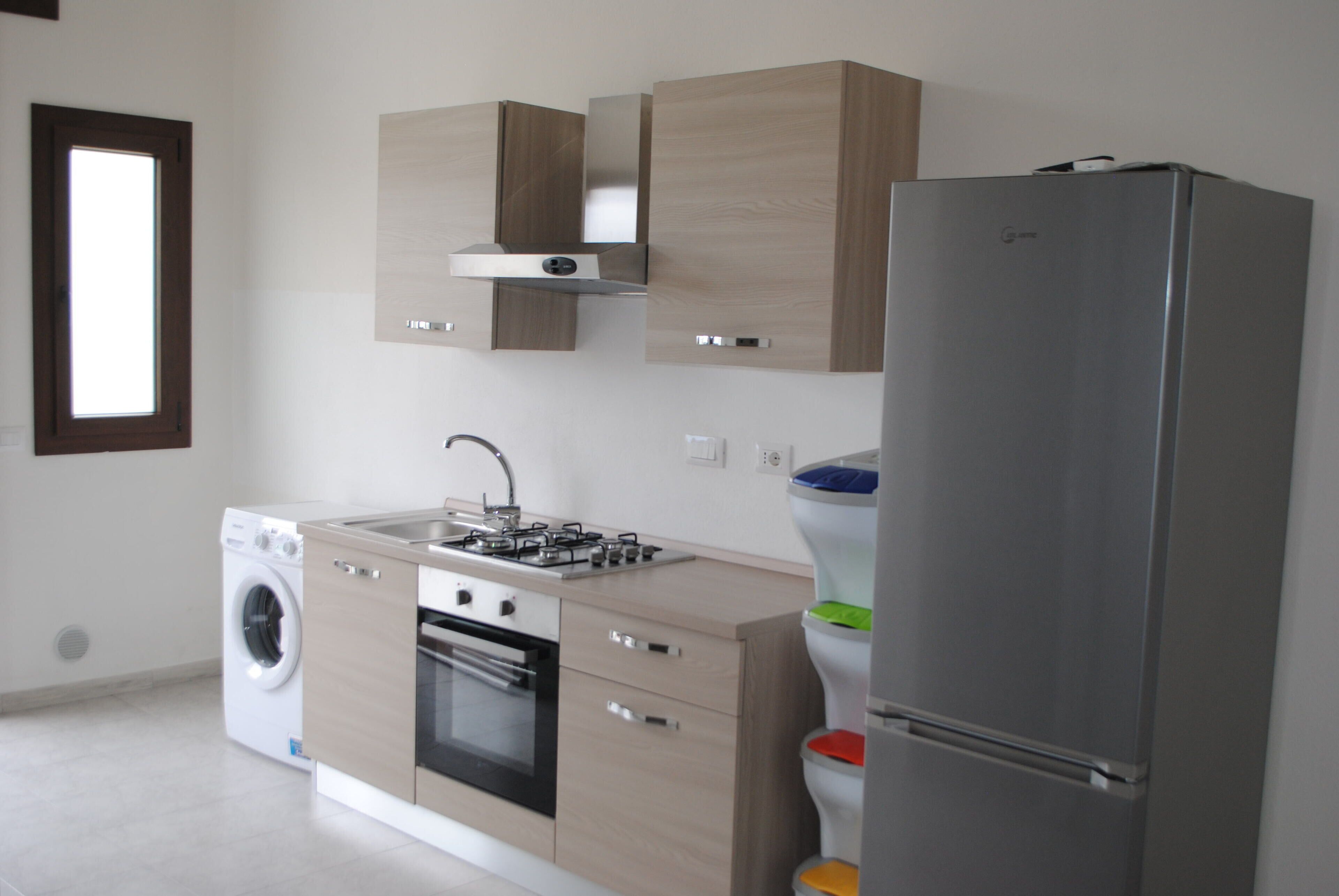 Eine moderne Küche mit Waschmaschine, Backofen, Spüle und einem großen Kühlschrank.