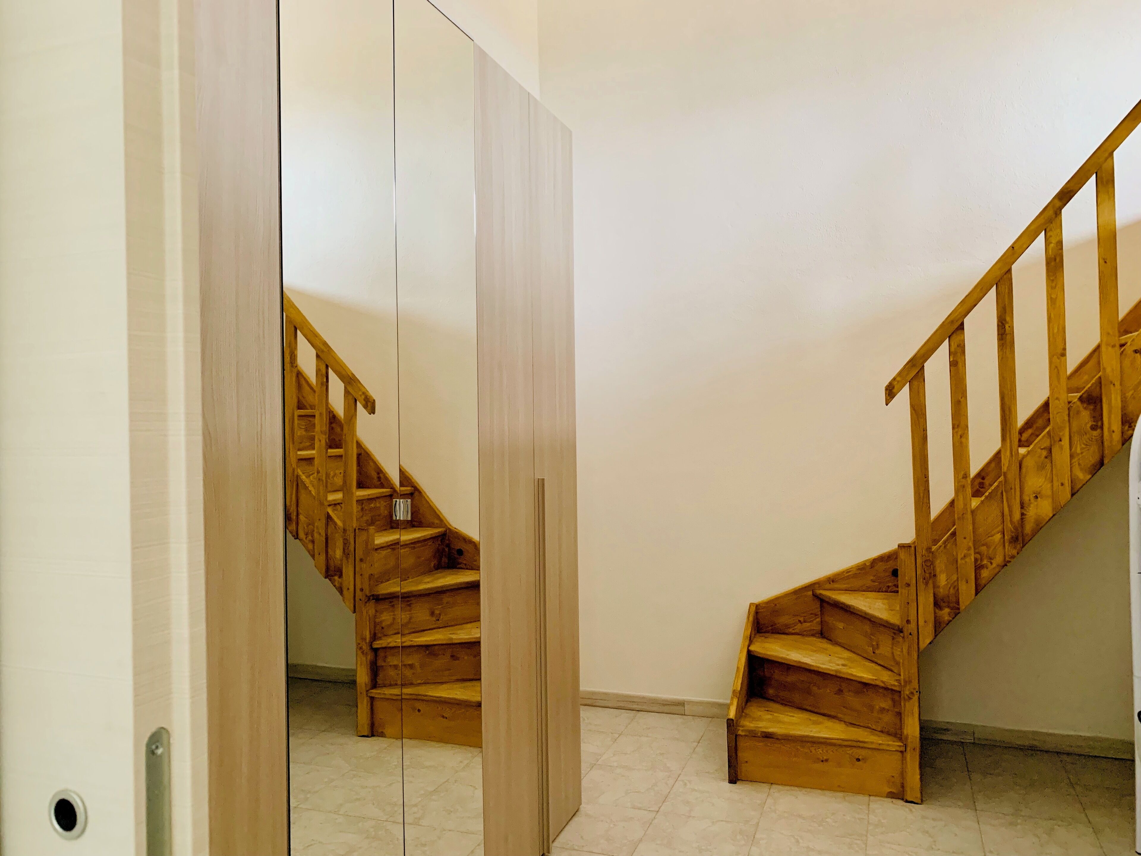 A wooden staircase with a handrail, leading to an upper floor.