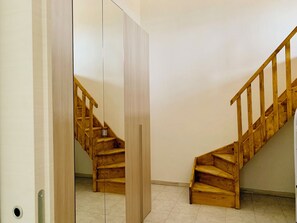 A wooden staircase with a handrail, leading to an upper floor. - Luxar Room (Assemini)