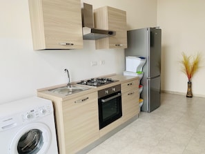 Una cucina moderna con mobili in legno, un frigorifero in acciaio inossidabile, un forno integrato e una lavatrice.