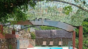 Una terraza de madera con bancos, una piscina y un pérgola con un letrero que dice 'SOLAR SEBOLIDO'.
