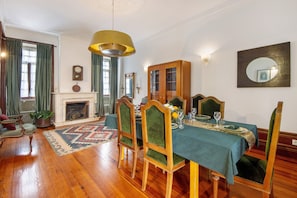 A dining room with a wooden table, chairs, a fireplace, and a large mirror on the wall.