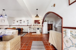 A cozy living area with a sofa, a dining table, and a kitchen in the background.