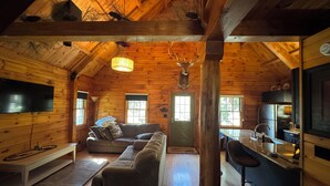 A cozy log cabin interior with a living room, kitchen, and dining area. - Log Cabin on the Clarion River! The Dam Inn 1 mile, 5 miles to East Branch Dam (Wilcox)