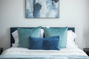 A bed with teal and white bedding, a dark headboard, and a painting above. - The Swayze, 3BR Retreat by Velvet Ditch Villas (Oxford)