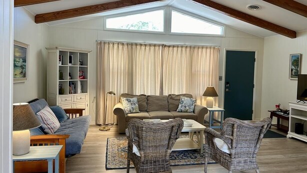 A spacious living room with a high ceiling, built-in bookshelves, a sofa set, and wicker chairs. - Cozy 4BR Beach House Retreat (Bethany Beach)