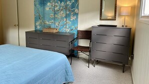 A bedroom with a bed, two dressers, a chair, a painting, and a mirror. - Cozy 4BR Beach House Retreat (Bethany Beach)