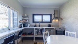 A compact kitchen with a window, a stove, a sink, and a dining area.