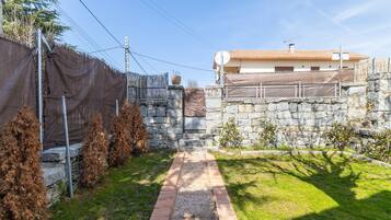 Un muro de piedra, un sendero de ladrillo y un edificio con tejado de tejas.
