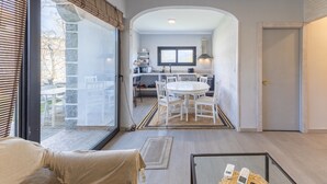 A modern interior with a dining area, kitchen, and large windows.