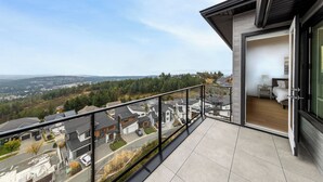 Un balcon donnant sur un quartier résidentiel, une chambre avec un lit et une table de chevet, et une porte-fenêtre coulissante qui mène à la pièce.