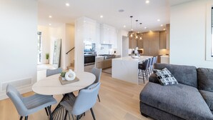 Une cuisine moderne avec des meubles blancs, un îlot central et un coin repas comprenant une table ronde et des chaises.