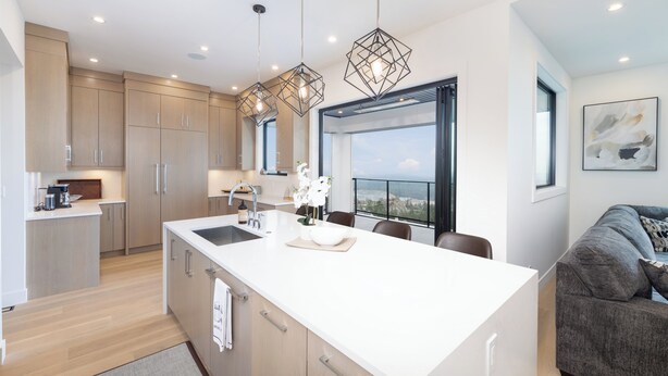 Une cuisine moderne dotée d’un grand îlot central, de meubles en bois et de luminaires suspendus.