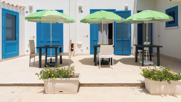 A terrace with outdoor seating, blue shutters, and potted plants. - Cozy, with garden, parking space, and 5 minutes from cornino bay beach (Sicilia)