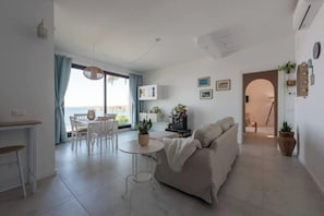 Ein modernes Wohnzimmer mit einer Couch, einem Esstisch und einer kleinen Küchenzeile.