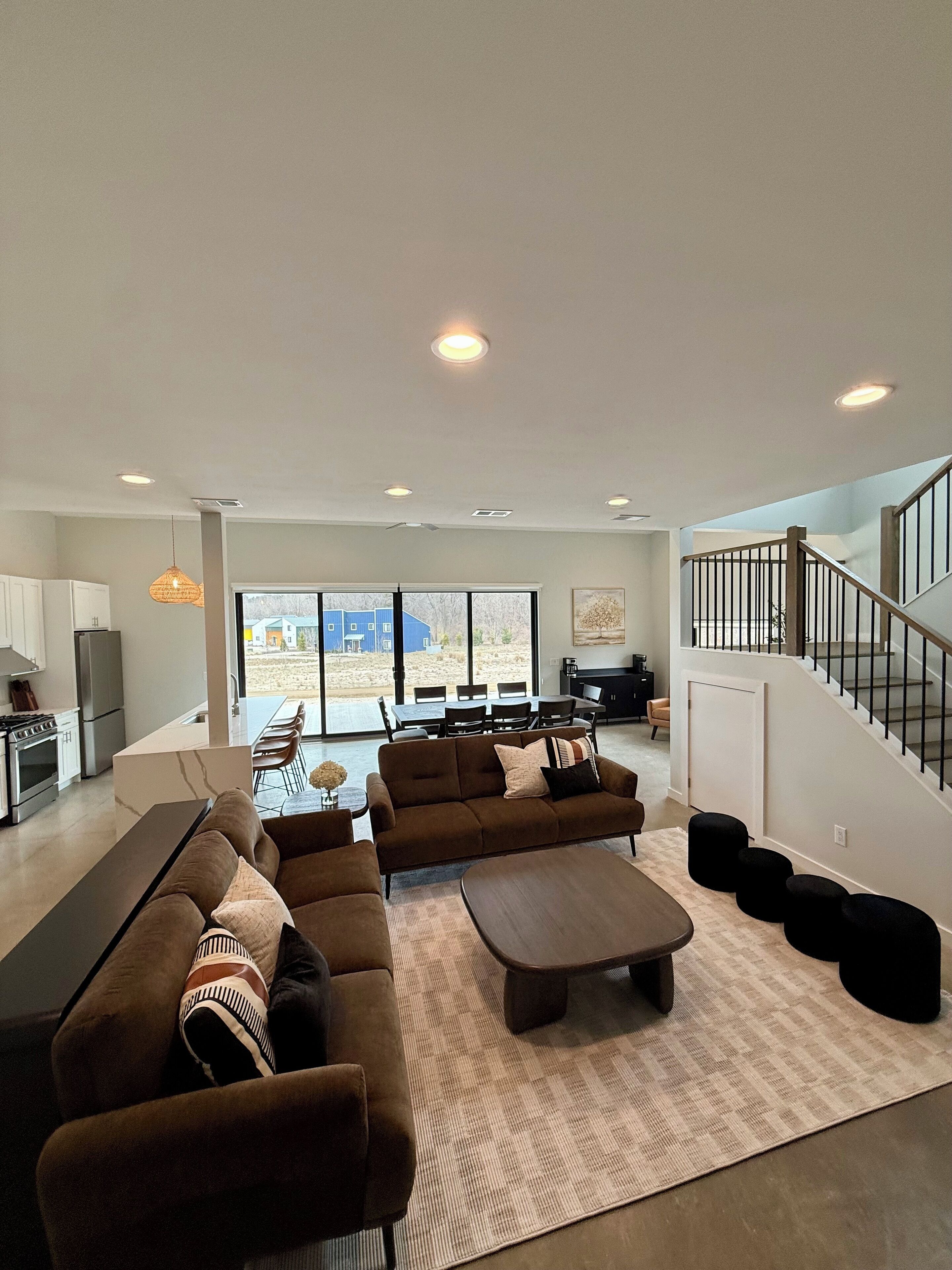 A modern living space with a sofa set, a dining table, and a kitchen area.