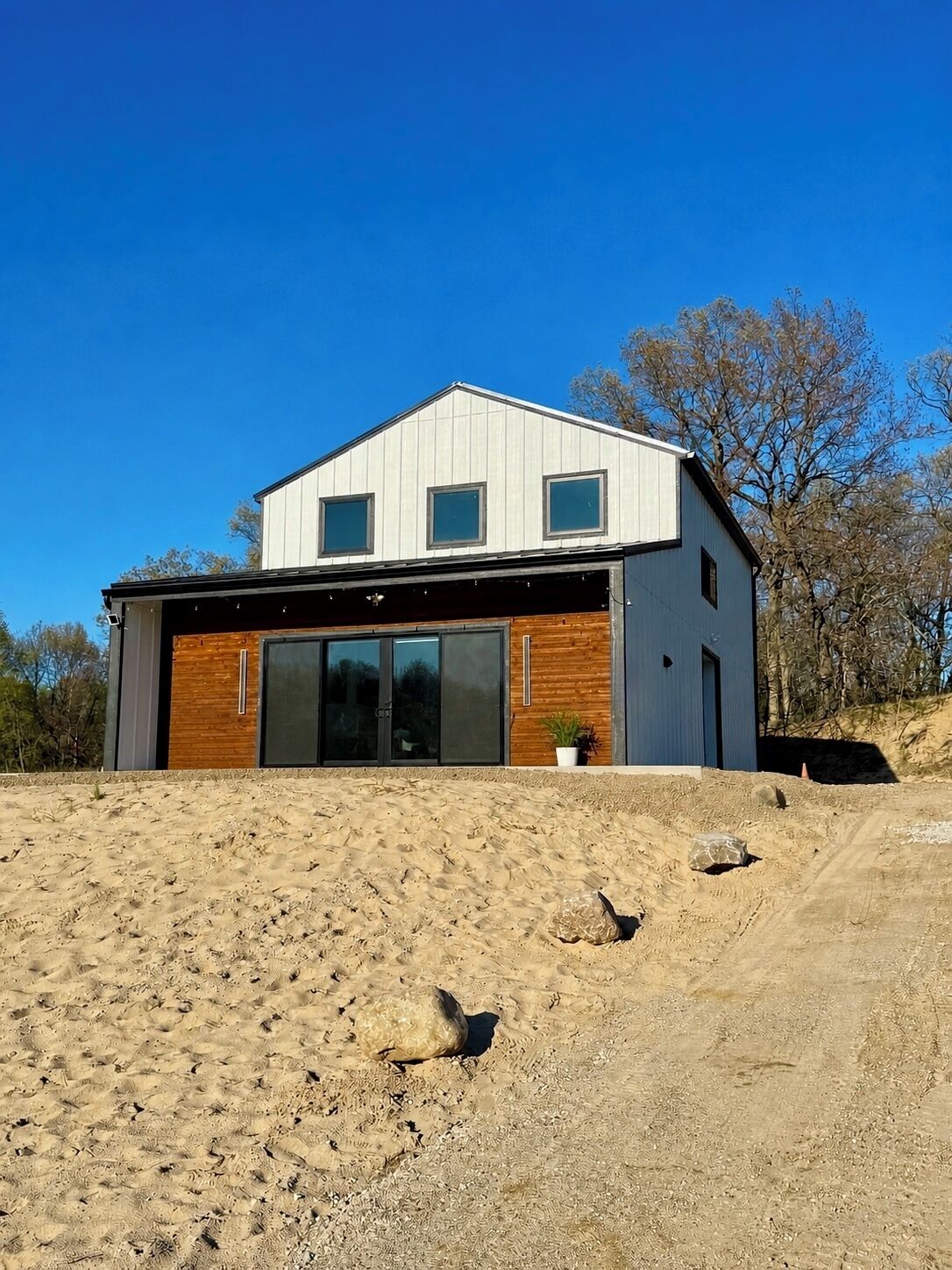 Une maison moderne à deux étages, dotée d’un garage, de grandes fenêtres et d’une façade en bois.