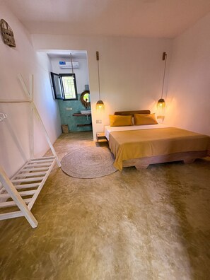 Een slaapkamer met een bed, nachtlampjes, een kleed en een raam.