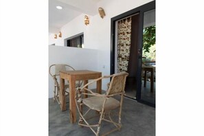 Een kamer met een houten tafel, een rieten stoel, een schuifglasdeur en een gordijn met patroon.