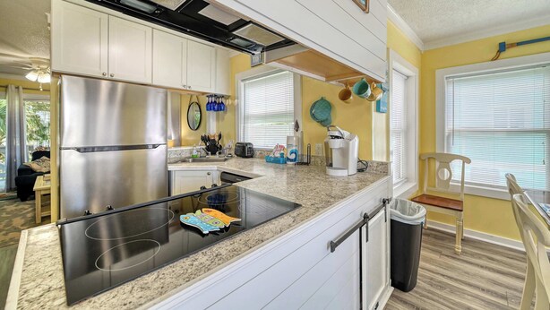 A kitchen with white cabinets, a stainless steel refrigerator, a built-in stovetop, and a coffee maker. - A Beach Escape- 1973 New River Inlet Rd (North Topsail Beach)