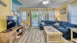 A living room with a TV, sofa, coffee table, and ceiling fan. - A Beach Escape- 1973 New River Inlet Rd (North Topsail Beach)