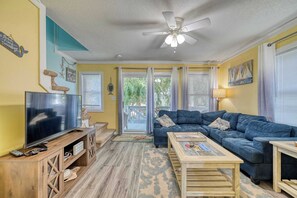 A living room with a TV, sofa, coffee table, and ceiling fan. - A Beach Escape- 1973 New River Inlet Rd (North Topsail Beach)
