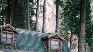 A rustic cabin with a porch, wooden deck, and a staircase leading to the entrance.
