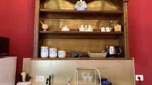 Una cucina con mensole in legno che ospitano diversi utensili da cucina, un bollitore e una macchina per il caffè.