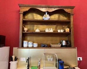 Eine Küche mit Holzregalen, die diverses Küchengeschirr, einen Wasserkocher und eine Kaffeemaschine beherbergen.