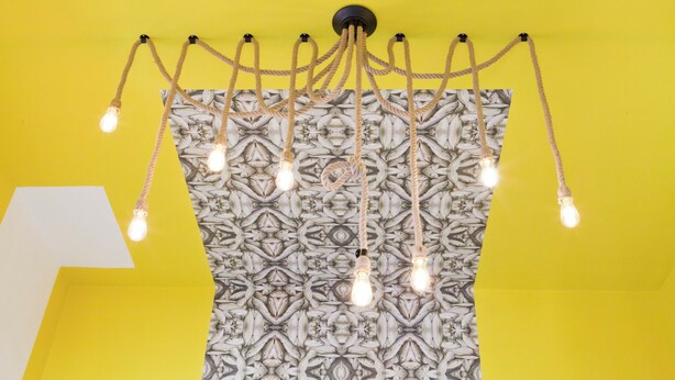 Un soffitto con una parete decorata e un lampadario con più lampadine.