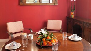 Una sala da pranzo con un tavolo rotondo apparecchiato per quattro persone, un grande specchio decorativo sopra il tavolo e un tavolino con un vaso di fiori.