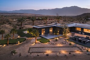 A modern house with a patio, outdoor seating, and a golf course.