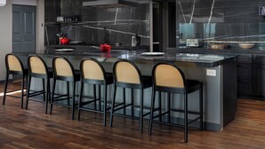 Une cuisine moderne dotée d’un îlot central, de meubles de rangement noirs et d’un pare-feu en marbre disposé en motif chevrons.