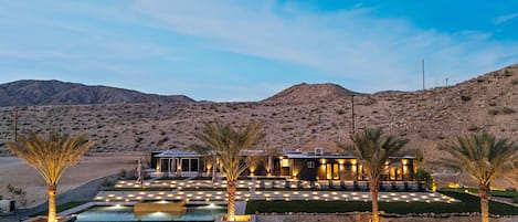 Ein Wüstenresort mit Pool, Außenbereich und Palmen.