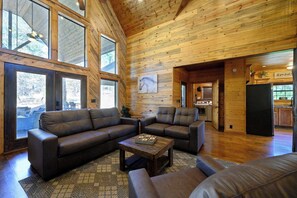 A spacious living room with leather sofas, a coffee table, and large windows. - Twisted Mane  prime location - family friendly (Broken Bow)