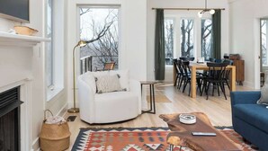 A spacious living room with a white sofa, a blue couch, a dining area with a table and chairs, and a fireplace. - Prime Location! 5 Min to National Park & Wineries (Afton)