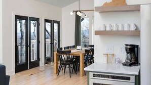 A modern kitchen with a dining area, featuring a coffee maker, a microwave, and a wooden dining table with chairs. - Prime Location! 5 Min to National Park & Wineries (Afton)
