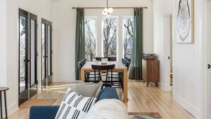 A modern living room with a sofa, a dining table with chairs, a coffee table, and a pendant light. - Prime Location! 5 Min to National Park & Wineries (Afton)