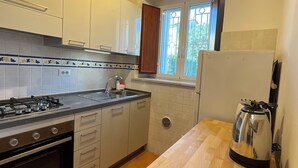 Une cuisine avec des meubles en bois, une cuisinière à gaz, un évier et une fenêtre donnant sur un paysage verdoyant.