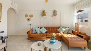 A living room with a brown sofa, two white round tables, and decorative wall art. - Ocean View La Caleta (La Caleta)
