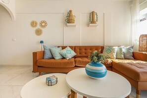 A living room with a brown sofa, two white coffee tables, and decorative items on the wall. - Ocean View La Caleta (La Caleta)
